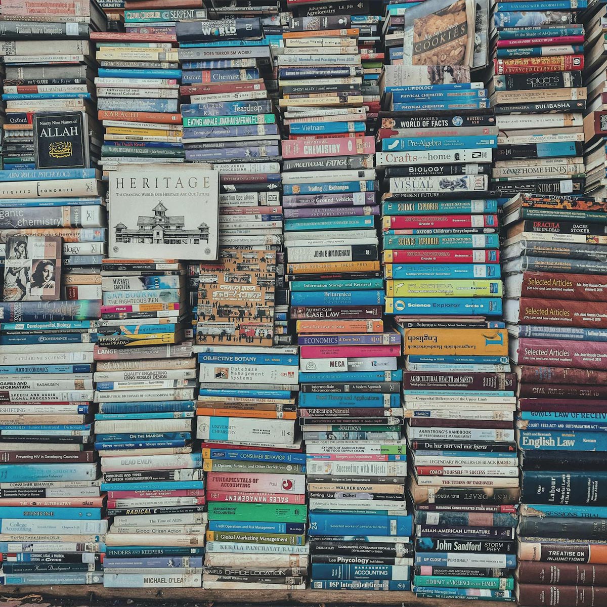 Woman picking up books on a large bookshelf.